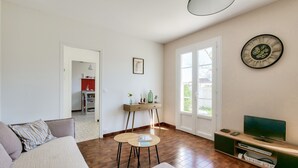 A living room with a sofa, coffee table, TV, and wooden flooring.