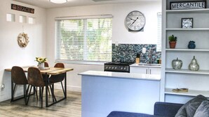 A modern kitchen with a clock, a dining area with chairs, and a living area with a couch.