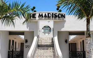 Hotellin sisäänkäynti, jossa on kyltti, jossa lukee ”THE MADISON”, portaikko ja palmuja.