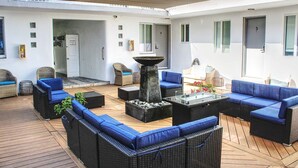 Un espace extérieur aménagé, abrité et doté de mobilier en osier, avec un foyer central.