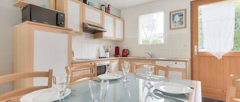 A modern kitchen with wooden cabinets, a microwave, and a dining table set for four.