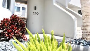 A modern building with a large number '329' on the facade, a staircase, and a well-maintained garden area with rocks and plants. - Spring break Retreat in Hollywood Beach (Hollywood)