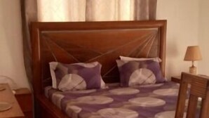Una camera da letto con un letto di legno, un baldacchino, un tavolo di legno e una sedia.