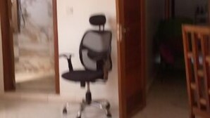 Una stanza spaziosa con un'ampia area aperta, una sedia da ufficio nera e una sedia di legno.