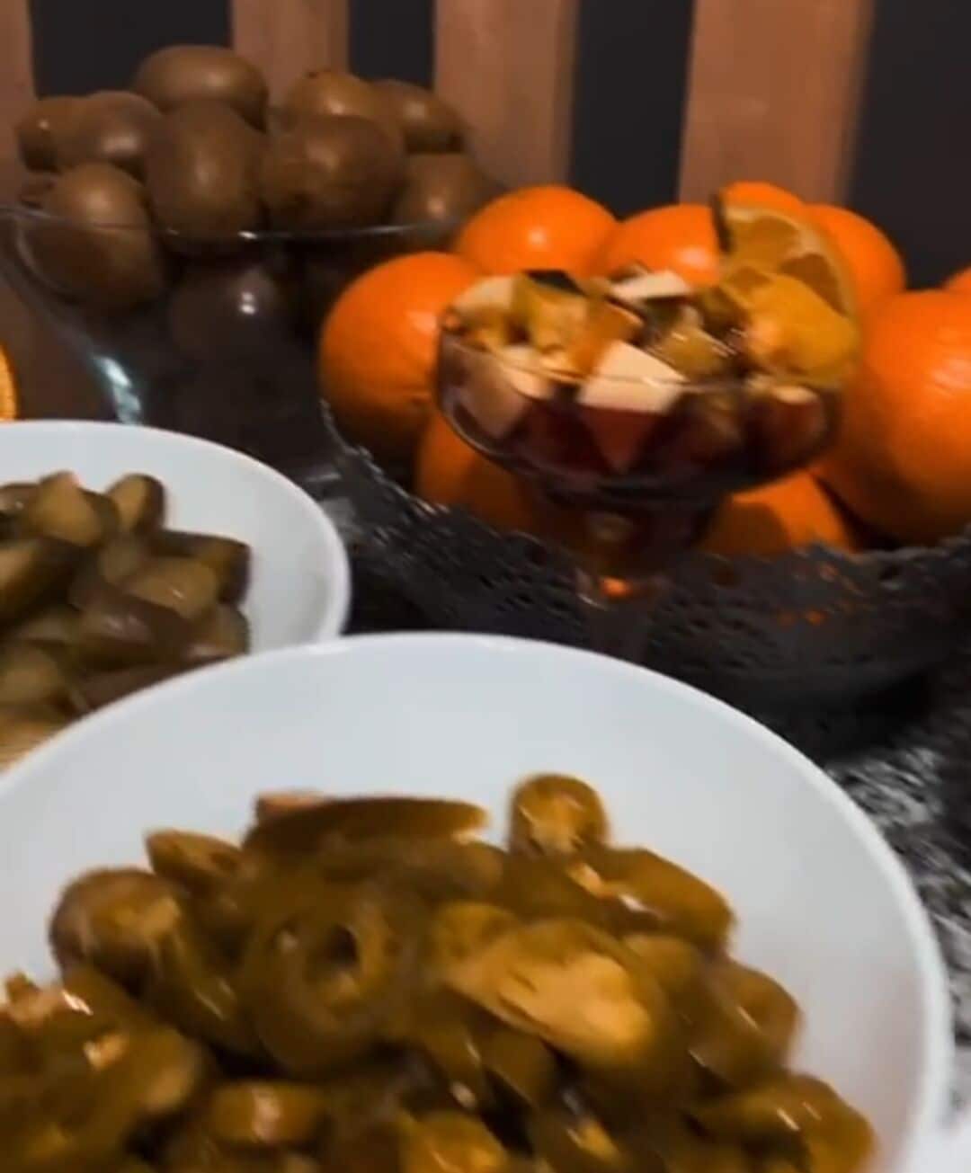Una mesa con fuentes de comida, entre ellas patatas en rodajas, naranjas y un plato con salsa marrón.