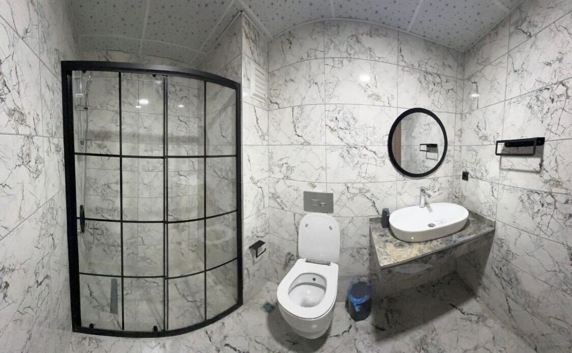 Un baño con ducha de vidrio, inodoro y lavabo con espejo.