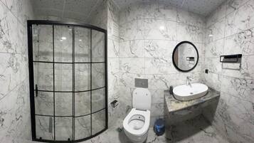 Un baño con ducha de vidrio, inodoro y lavabo con espejo.