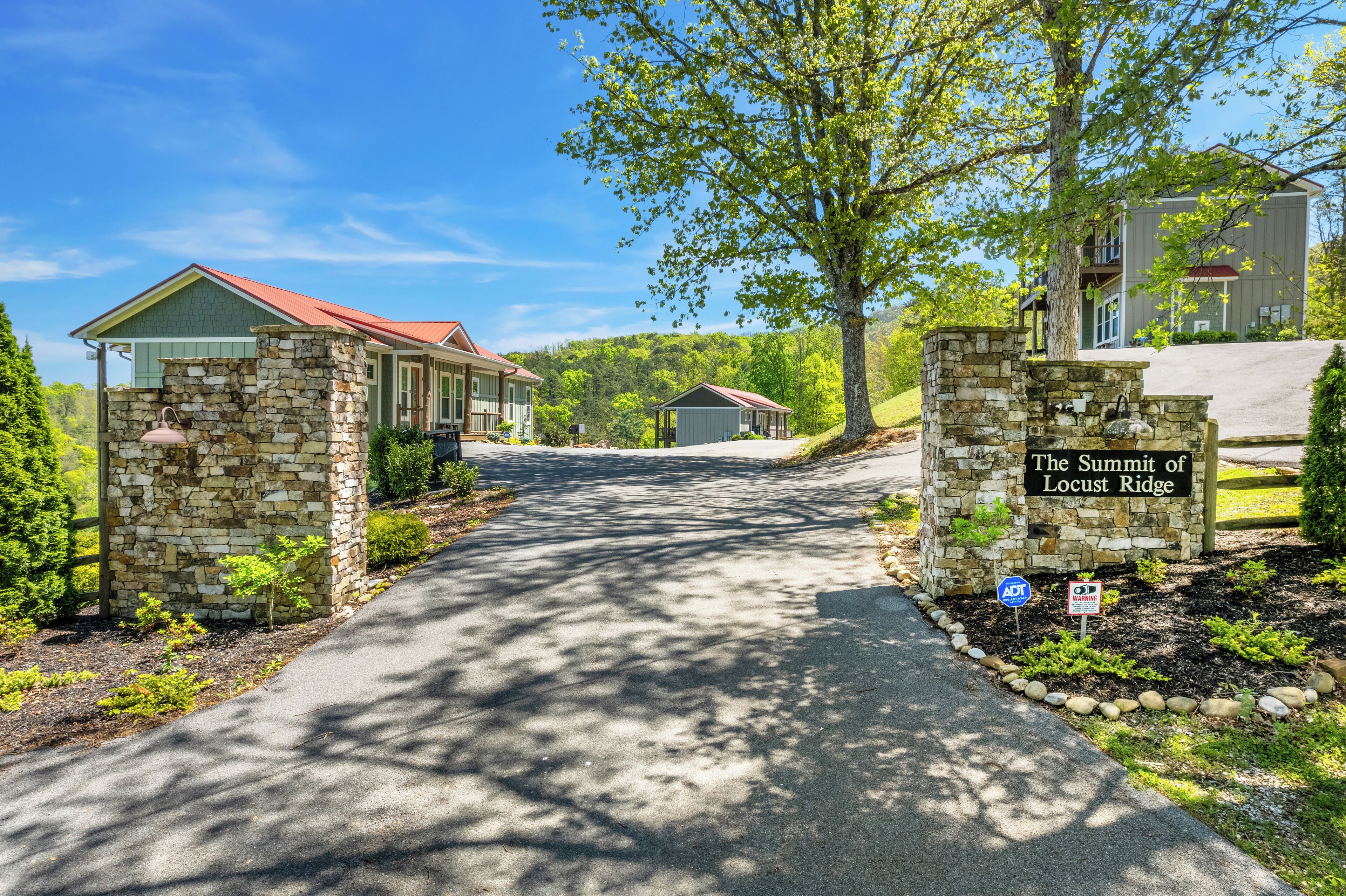 A gated entrance to a property named 'The Summit of Locust Ridge' with a paved driveway leading to a building with a red roof.