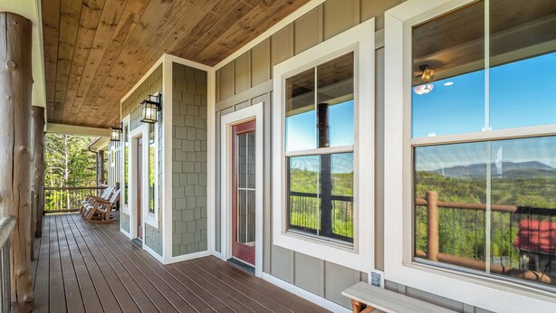 Une terrasse en bois avec un banc, de grandes fenêtres et une vue sur le paysage.