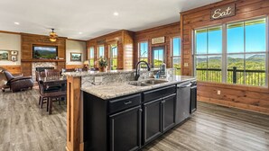 Une cuisine spacieuse dotée d’un grand îlot central, de murs en bois et d’un coin repas offrant une vue sur les montagnes.