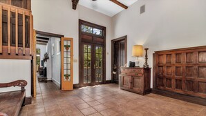 A spacious hallway with a wooden bench, a large wooden door, and a cabinet with a lamp. - Wolf Creek House (Black Mountain)