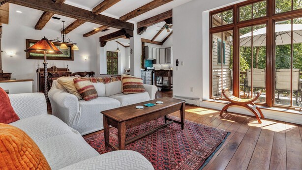 A spacious living room with a wooden ceiling, a large window, and a cozy seating area. - Wolf Creek House (Black Mountain)