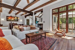 Een ruime woonkamer met een houten plafond, een groot raam en een gezellige zithoek.