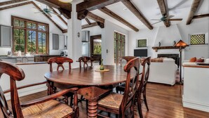 A spacious dining area with a wooden table and chairs, a kitchen in the background, and a cozy seating area with a white sofa. - Wolf Creek House (Black Mountain)