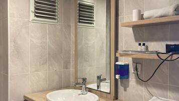 A modern bathroom with a large mirror, a sink, and a towel rack.