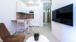 A modern living room with a sofa, a dining table, and a TV mounted on the wall. - Modern Apartment -2bdr/6p - 300m From the Beach (Antibes)