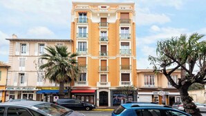 A multi-story hotel with balconies, a central entrance, and various storefronts on the ground floor. - Modern Apartment -2bdr/6p - 300m From the Beach (Antibes)