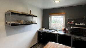 A compact kitchen with a wooden countertop, a built-in shelf with dishes, a window, and a microwave. - Viana do castelo Villa rioneiva (Alvarães)