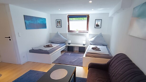A compact living space with a sofa, a small table, and two beds. - Cozy 2 room apartment for 2-4 persons between Kiel-City and the beaches (Schönkirchen)