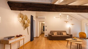 Una sala de estar moderna con piso de madera, un sofá marrón, una mesa de centro redonda y una consola de madera con libros.