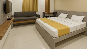 Una habitación de hotel moderna con una cama grande, un sofá, un escritorio y un televisor.