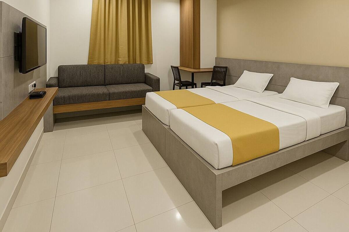 Quarto de hotel moderno com uma cama grande, um sofá, uma escrivaninha e uma televisão.