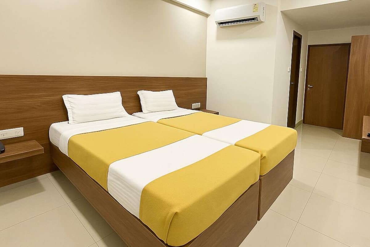 Quarto de hotel com uma cama grande, um ventilador de teto, ar condicionado e um guarda-roupa de madeira.