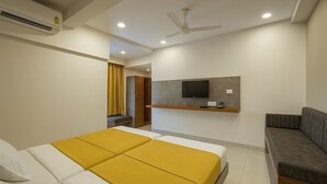 Una habitación de hotel con cama, sofá, televisión montada en la pared y ventilador de techo.