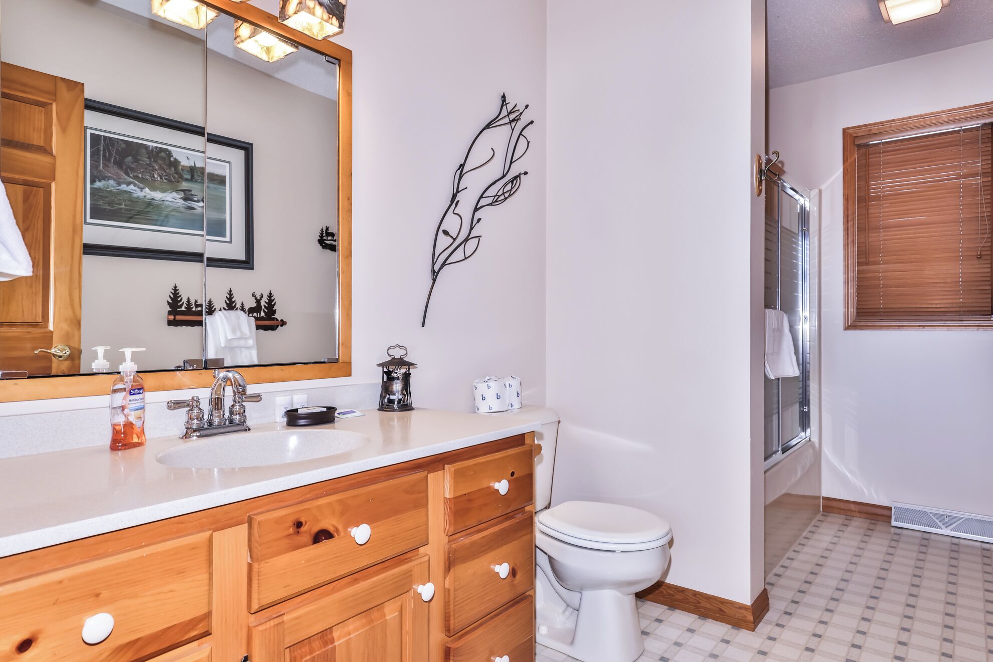 A bathroom with a wooden vanity, a white toilet, a shower with a glass door, and a wall-mounted mirror.