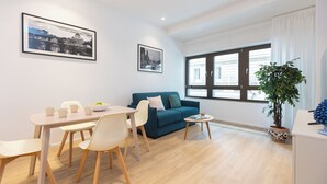 Un salon moderne comprenant un coin repas, un canapé bleu et une grande fenêtre avec des rideaux.