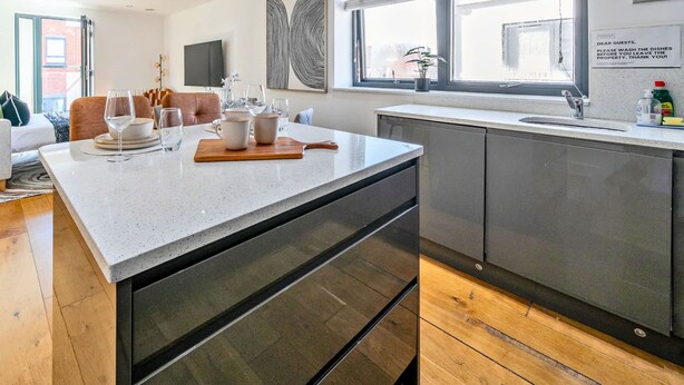 Et moderne køkken med en stor ø, et spiseområde med en sofa og udsigt over byen.