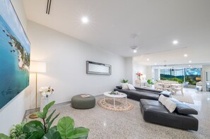 Ein modernes Wohnzimmer mit einem großen Gemälde, einer Couch, einem Couchtisch und einem Essbereich im Hintergrund.