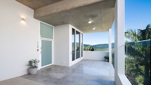 Un balcón moderno con suelo de hormigón, una planta en maceta y vistas a un paisaje montañoso.