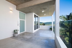 A modern balcony with a concrete floor, a potted plant, and a view of a mountainous landscape. - 23B Airlie View (Airlie Beach)