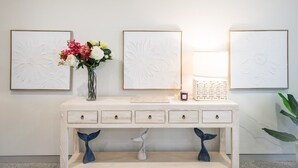 Una consola de madera con cuatro cajones, un florero con flores y tres cuadros enmarcados.