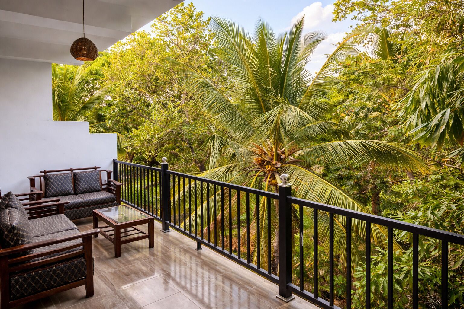 A balcony with a wooden sofa, a glass table, and a railing.
