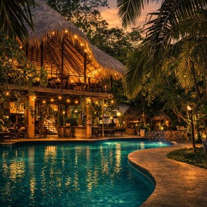 A pool area with a thatched-roof structure, a stone pathway, and lush greenery. - Sundaras Infinity Jungle Resort & Spa (Dambulla)
