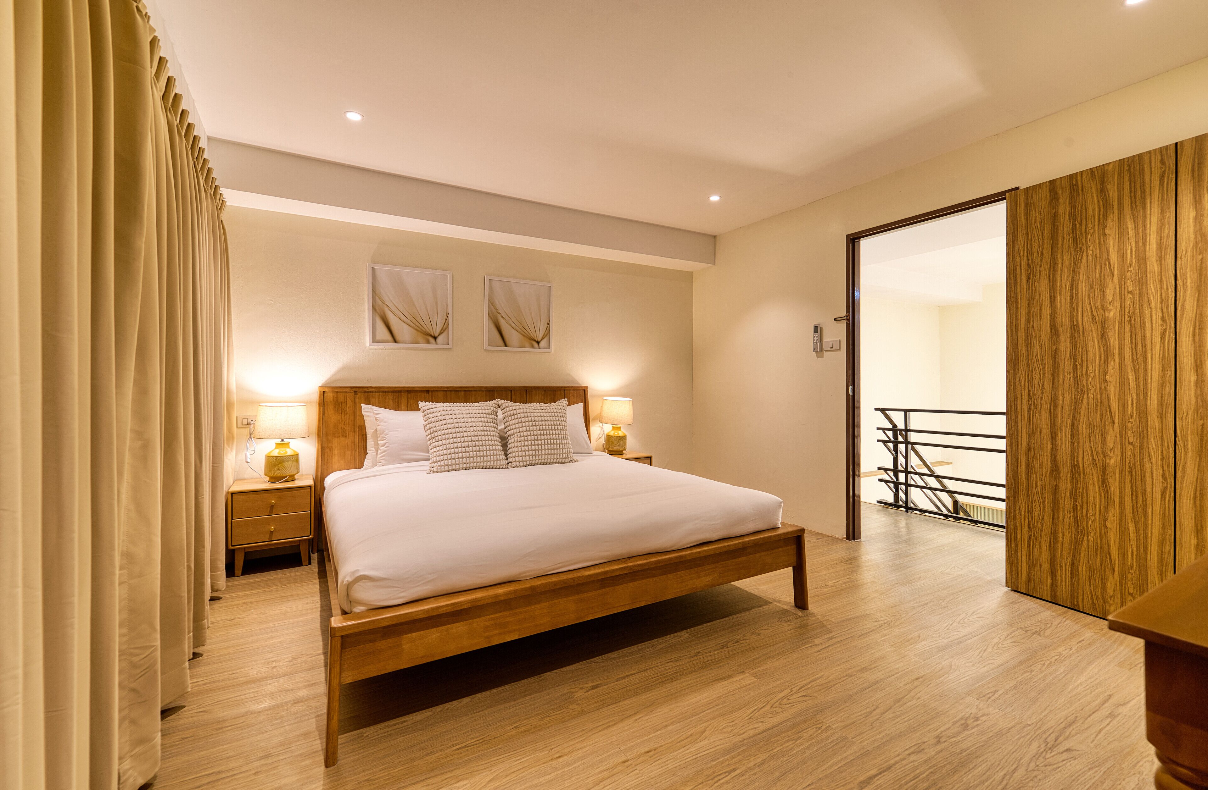 A modern bedroom with a wooden bed, two bedside lamps, and a wooden wardrobe.