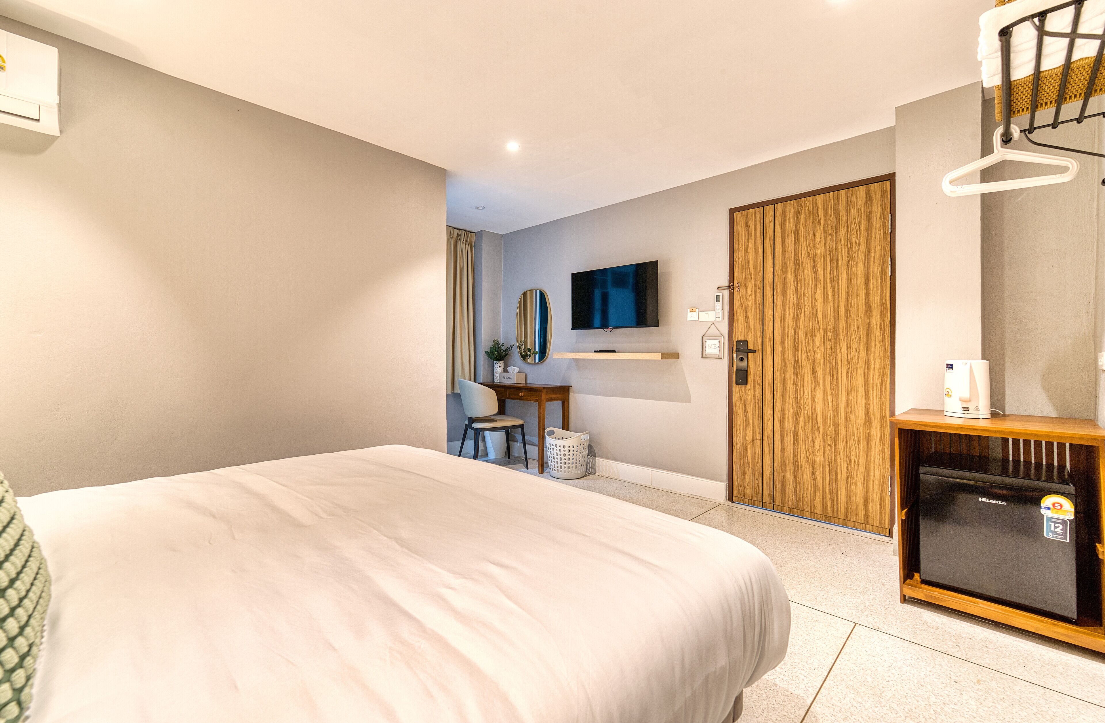 Una habitación de hotel con cama, escritorio, televisor y minibar.