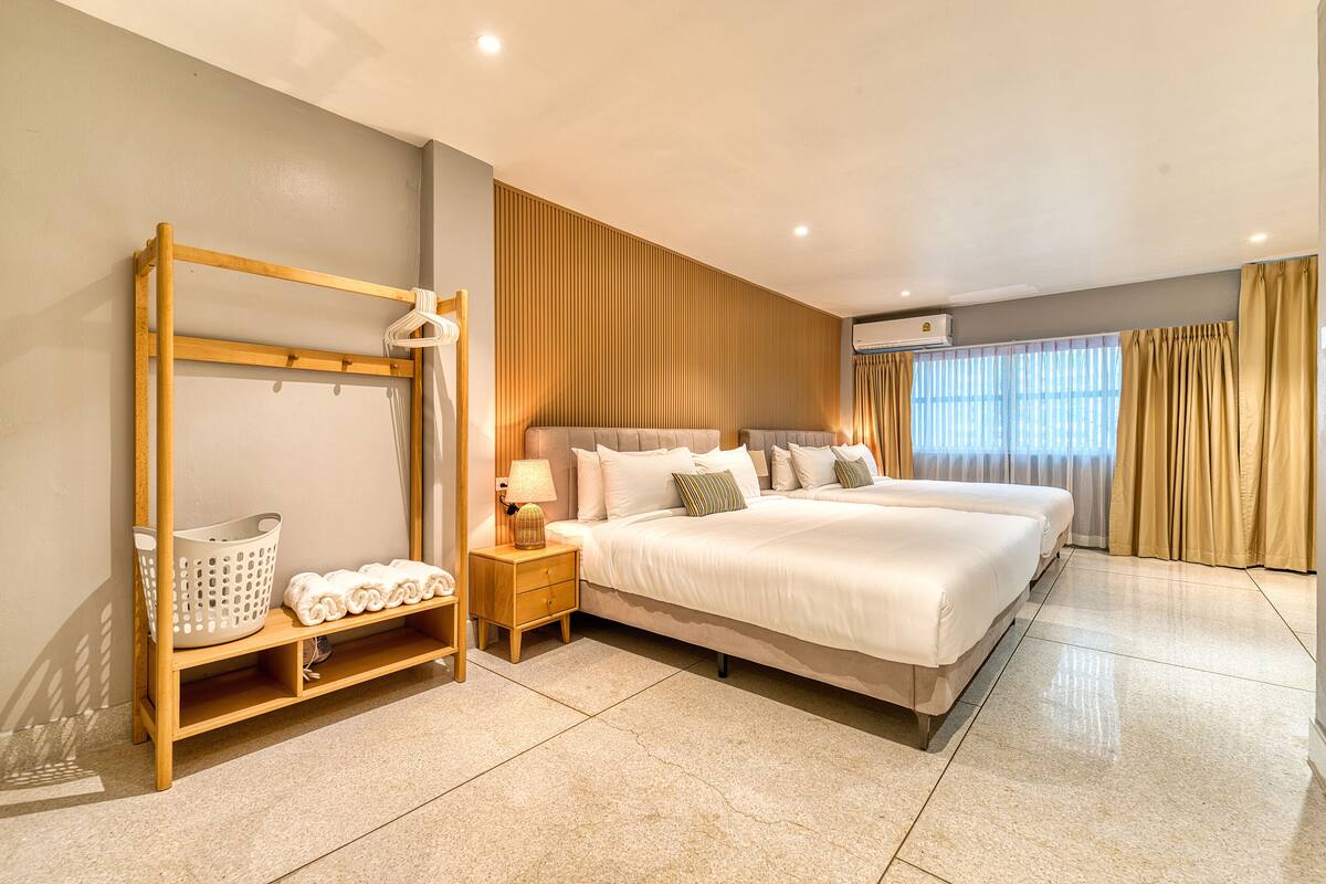 Ein geräumiges Schlafzimmer mit einem großen Bett, einem Holzschrank, einem Nachttisch mit Lampe und einem Fenster mit Vorhängen.