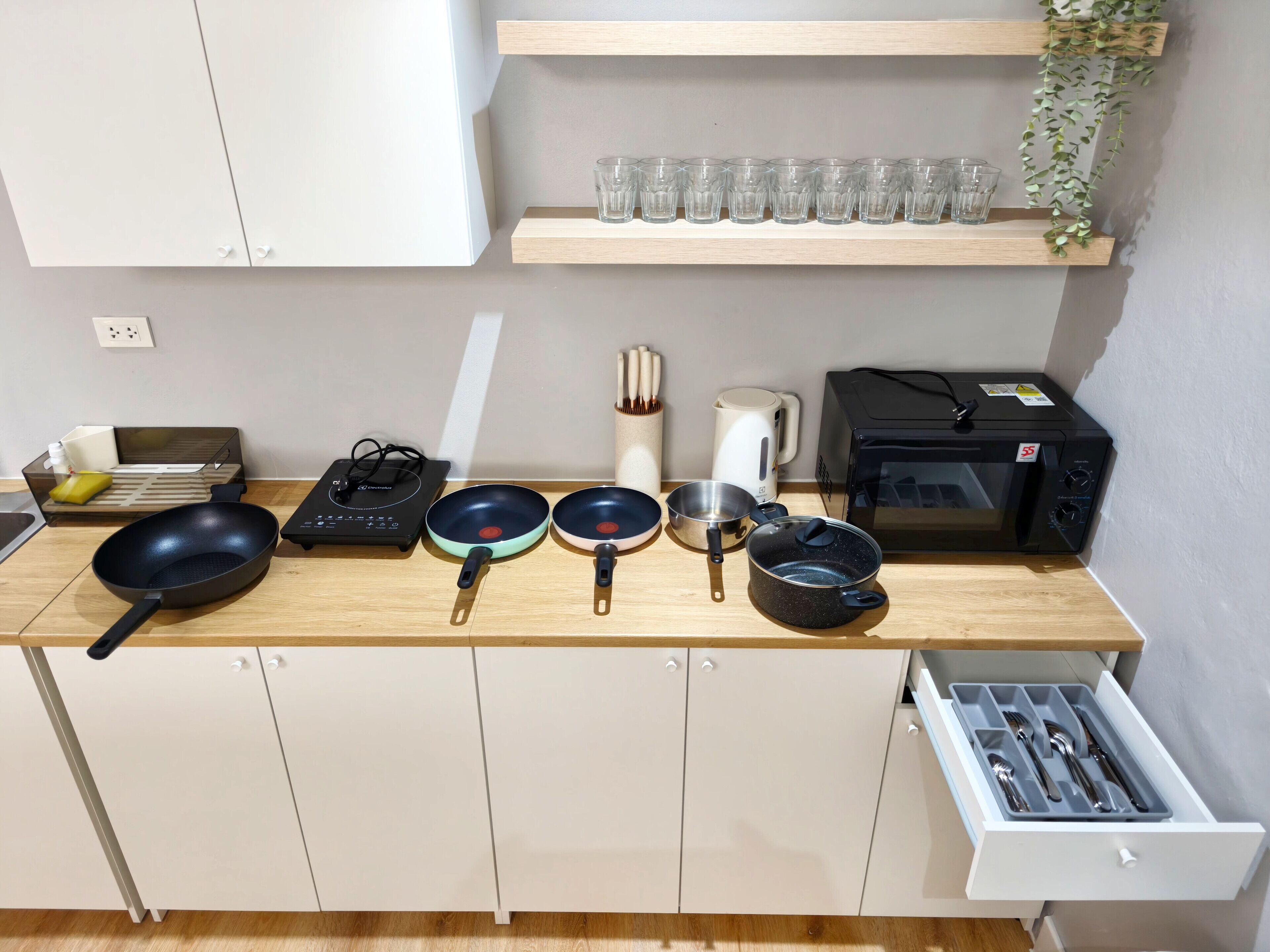 A kitchen with a microwave, toaster, and various cookware on the counter.