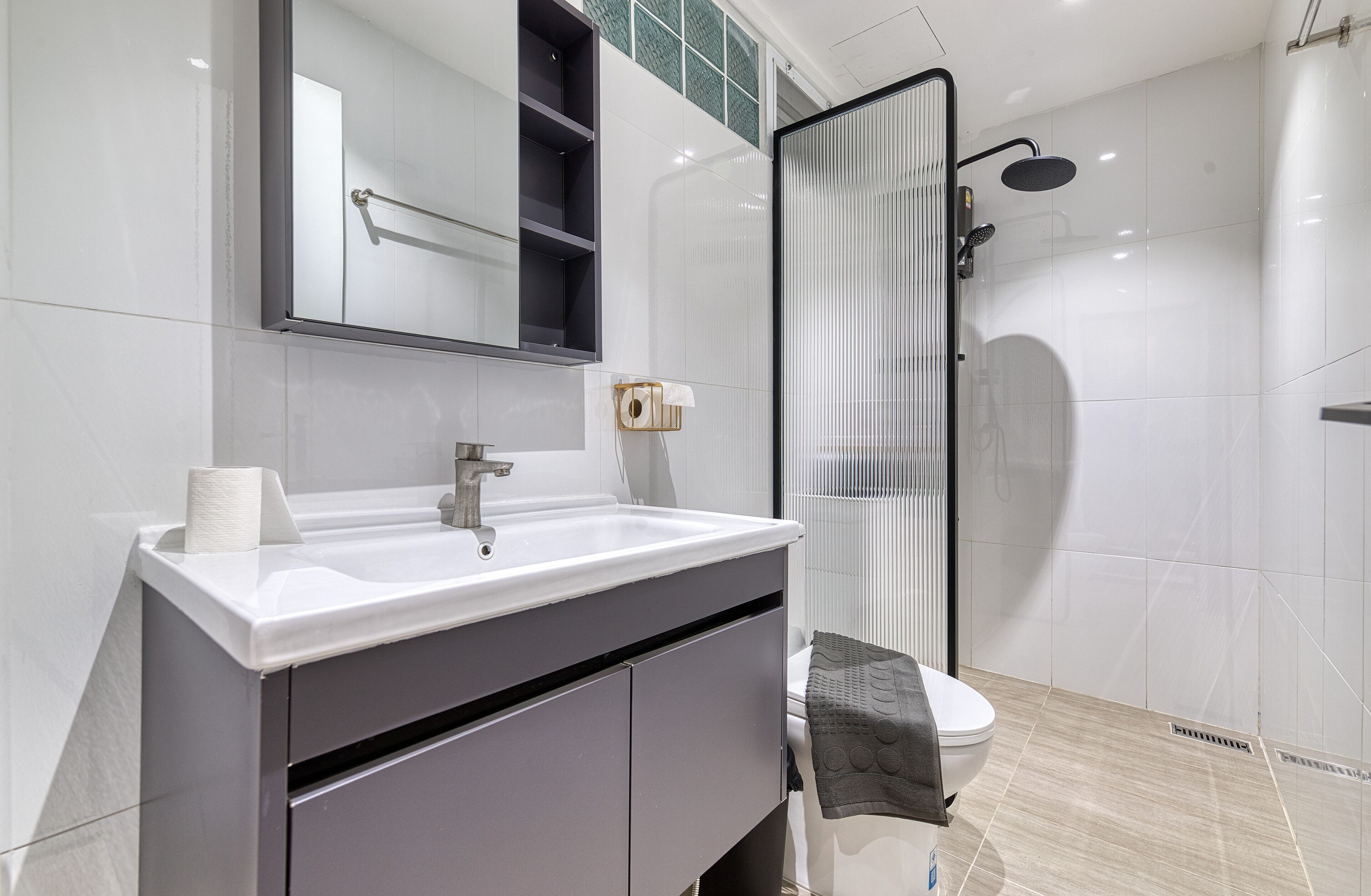 Een moderne badkamer met een witte wastafel, spiegel en douchecabine.