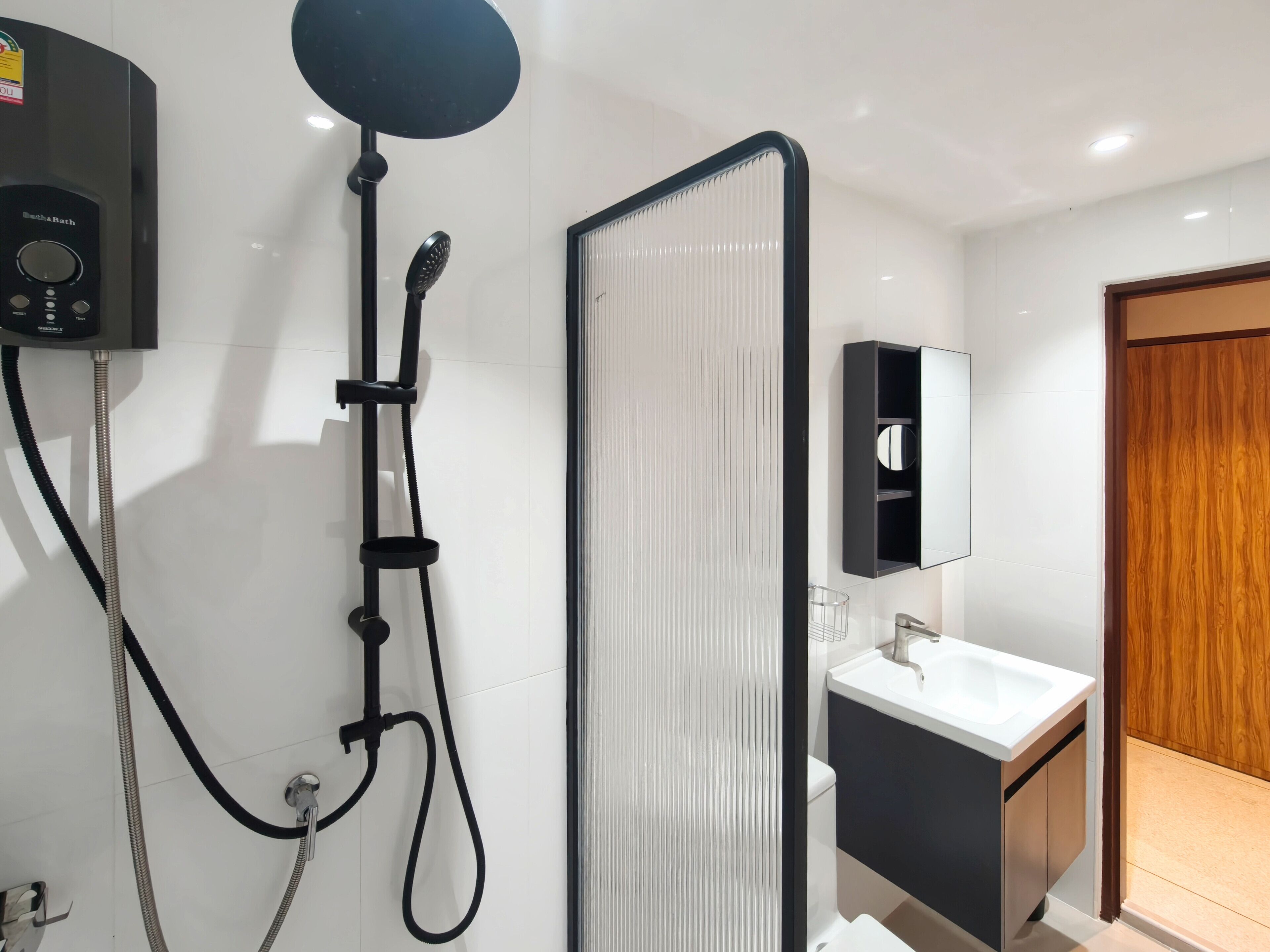 A modern bathroom with a shower, a toilet, a sink, and a mirror.