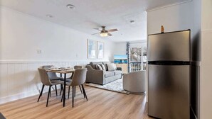 Een moderne keuken met een roestvrijstalen koelkast, een eethoek met een tafel en stoelen, en een plafondventilator.
