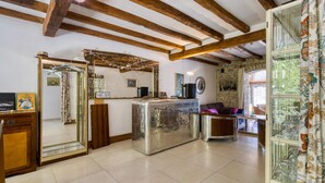 Uma sala de estar ampla com vigas de madeira aparente, parede de pedra e um espelho grande.