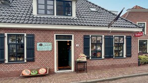 A brick building with a tiled roof, a signboard, and a small table outside.