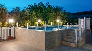 Una piscina rectangular con valla blanca y una escalera que lleva hacia ella.