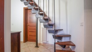 Una escalera moderna con escalones de madera y barandillas de metal, que conduce a una puerta de madera.