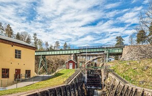 A bridge over a water channel with a small building and a yellow building in the foreground.