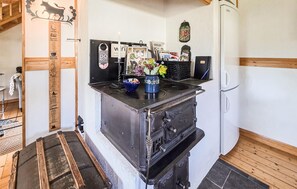 A compact kitchen with a stove, a refrigerator, and a wooden cabinet.